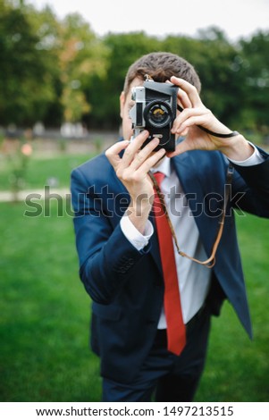 Young man holds an old camera in his hands.