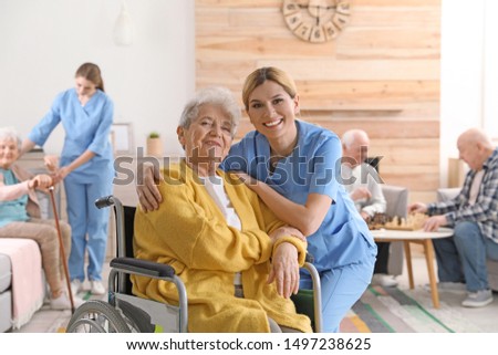 Nurse with elderly woman in wheelchair at retirement home. Assisting senior people Royalty-Free Stock Photo #1497238625