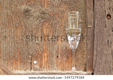 A wine glass with water in front of a wooden board