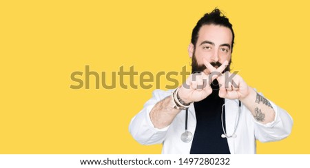 Doctor with long hair wearing medical coat and stethoscope Rejection expression crossing fingers doing negative sign