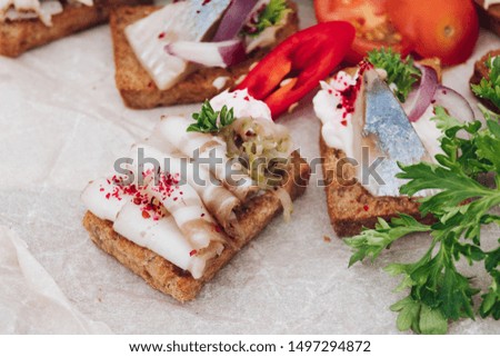 Delicious canapes with herring.Macro of delicious canape or sandwiches with fresh herring, black sesame, cream cheese on crispy bread.