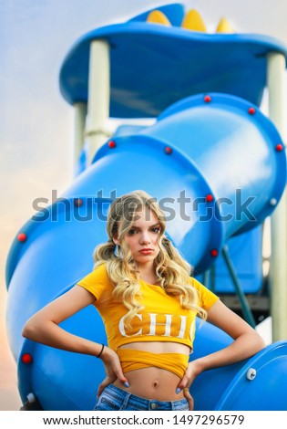 Super cool urban rebel teen girl with wavy long blonde hair posing on playground outdoor.Teen fashion editorial photography 