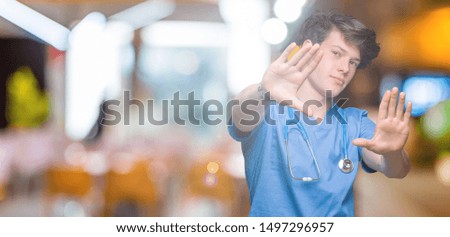 Young doctor wearing medical uniform over isolated background Smiling doing frame using hands palms and fingers, camera perspective