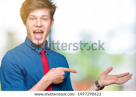 Young handsome business man wearing red tie over isolated background amazed and smiling to the camera while presenting with hand and pointing with finger.