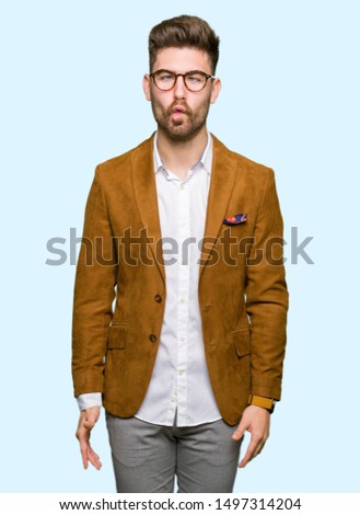 Young handsome business man wearing glasses making fish face with lips, crazy and comical gesture. Funny expression.