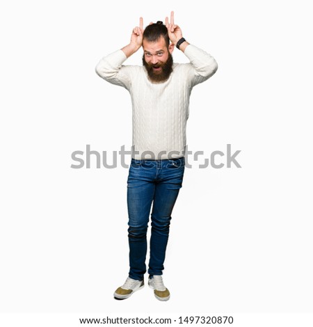 Young hipster man wearing winter sweater Posing funny and crazy with fingers on head as bunny ears, smiling cheerful