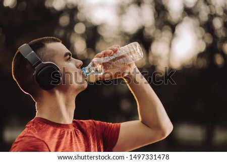 Profile of thirsty young man drinking water at sunset