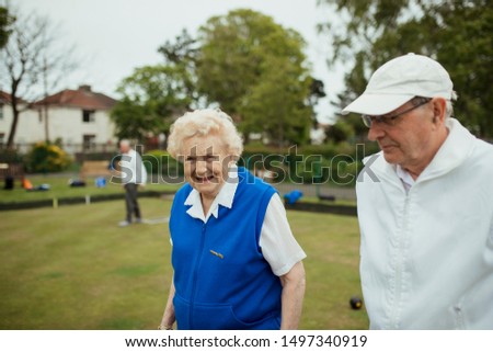 A front view shot of a senior couple smiling at a bowling green.