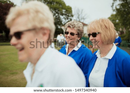 A side view shot of a group of senior women smiling at a bowling green.