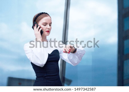 Serious business woman talking on the phone and looking at his watch. Worried phone conversation, look at the time. Female entrepreneur in business suit looking at watch on hand.