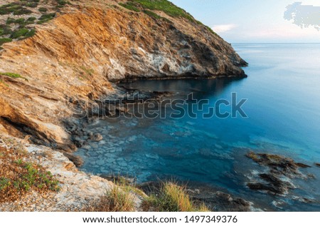 Beautiful sea bay at dawn, with clear water and black stones.