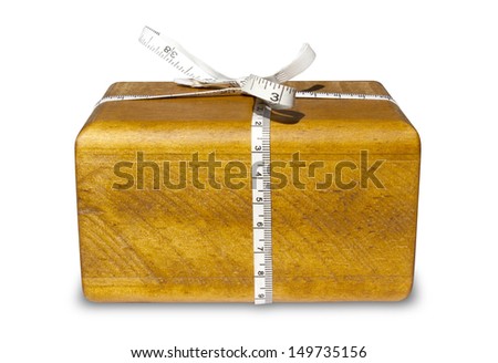 A block of wood with a tape measure tied around it resembling a gift on an isolated white background
