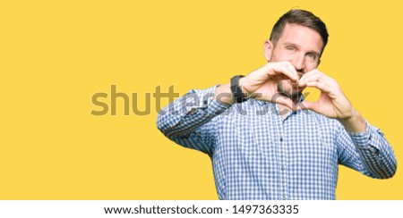 Handsome business man with blue eyes smiling in love showing heart symbol and shape with hands. Romantic concept.
