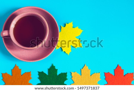 Cup of tea with decorative felt maple leaves. Top view. Autumn concept background