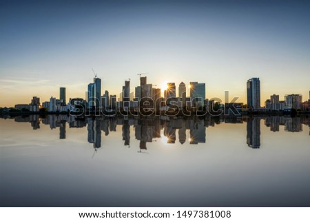 The skyline of London: financial district Canary Wharf during sunset with reflections in the river Thames, United Kingdom