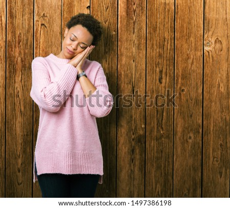 Beautiful young african american woman over isolated background sleeping tired dreaming and posing with hands together while smiling with closed eyes.