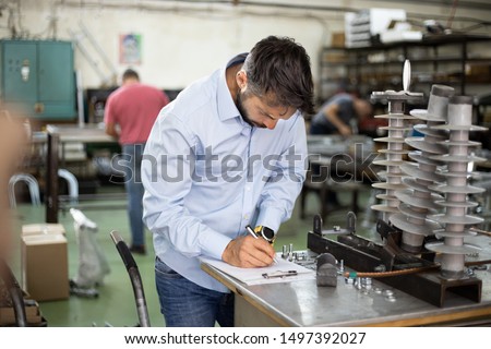 Middle age businessman doing quality control checking at industry production. Factory for industrial production of electric housings and surge arresters.