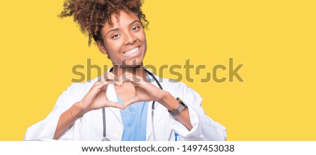 Young african american doctor woman over isolated background smiling in love showing heart symbol and shape with hands. Romantic concept.