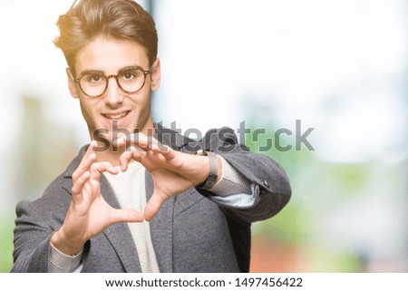 Young business man wearing glasses over isolated background smiling in love showing heart symbol and shape with hands. Romantic concept.