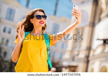 Portrait of her she nice attractive lovely pretty glamorous cheerful cheery positive girl wearing colorful yellow bright t-shirt taking selfie showing v-sign outdoors