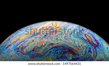 Macro picture of half soap bubble on black background look like colorful psychedelic planet in space