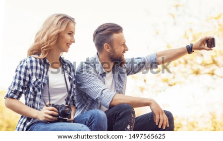 Young loving couple making selfie photo in autumn park.