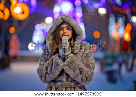 Girl in a gray coat in the winter. Girl makes a wish in Christmas. Beautiful picture of a girl in Christmas in blur
