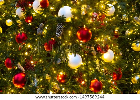 Close up of a lighted Christmas tree with golden lights, red and white ornaments