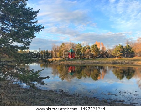 A picture of a Chinese Pavilion taken from across the lake showing the reflection of the pavilion and it's surroundings in the water. Taken in Kings Park, Winnipeg, MB.