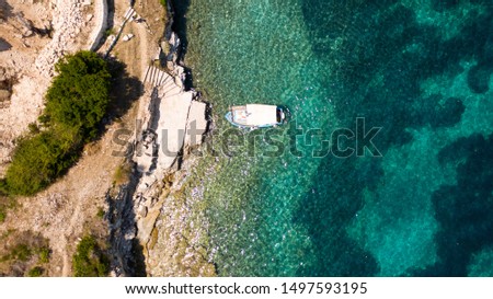 Aerial shot of a moored fishing boat on turquoise water at Paxos island, Greece
