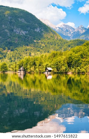 Scenery of wooden houses at Bohinj Lake in Slovenia. Nature in Slovenija. View of Beautiful landscape and blue sky in summer. Alpine Travel destination. Julian Alps mountains on scenic background