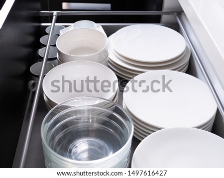 Kitchen furniture with plates stored in drawers, Counter cabinet to store containers Food utensils with ceramic dishes and glass cup.