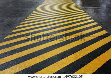 Yellow-black signal strip at the factory. Floor painting for worker safety. Allocation of hazardous areas. Safety in a factory or factory. Macro photo. Royalty-Free Stock Photo #1497632105