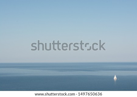 Minimalist picture of white sailboat in calm blue sea