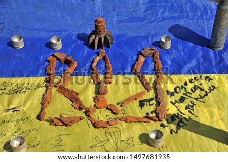 Emblem of ukraine is laid out from the fragments of mines and shells against the background of the battle flag. Russian-Ukrainian war on the Donbass.