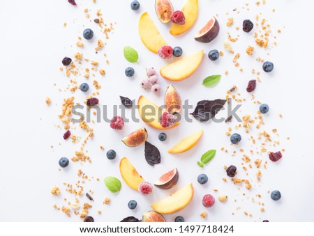 Pattern of fresh peaches, figs, berries, cereal and mint leaves isolated on a white background, top view. Healthy vegan breakfast concept