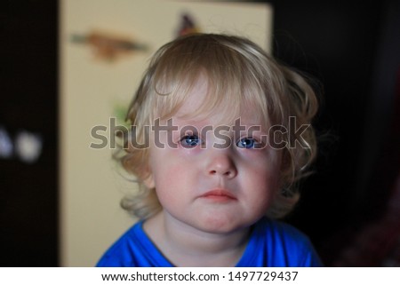 Portrait of a crying boy. Kid with sad expression looking TV. Emotions on the face of baby.