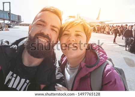 Smiling millennial couple taking selfie during airport departures. Real people lifestyle vacation, toned