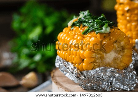 Baked corn with spiced butter on a rustic wooden background. Food for the holidays and barbecue. Autumn harvest.