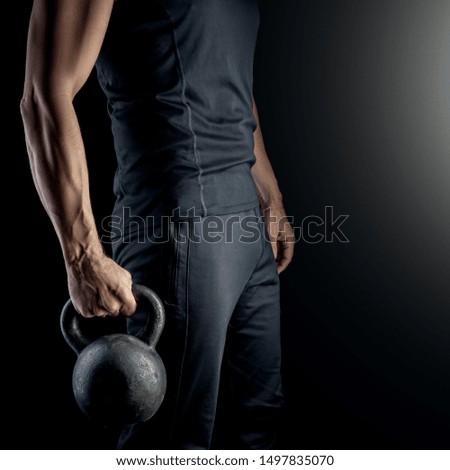 Athlete with a kettlebell in his hand on a black background