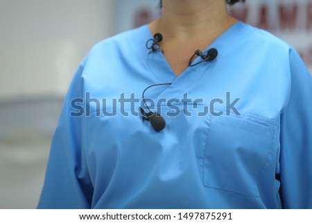 Details with many lavalier microphones on the medical coat of a woman medic