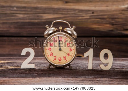 Farewell to the Old Year 2019. There are numbers and a red clock on the background of old wood