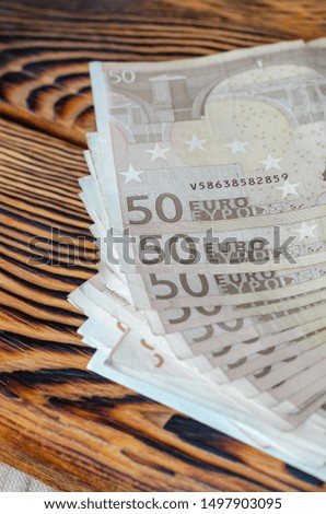 Close-up money. Banknotes of 50 euros are on a brushed wooden table. Selective focus. Removed color accent from money. The vertical arrangement of the photo.