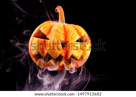 On a black background is a pumpkin and it is smoke . Scary decoration on Halloween