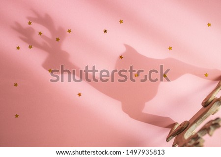Wooden deer decoration on pink background with deer shape shade. Christmas concept. New Year decoration 