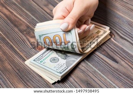 Perspective view of female hands counting money. One hundred dollar banknotes on wooden background. Salary concept. Bribe concept.