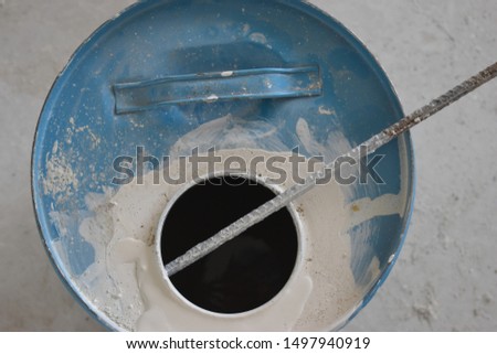 A blue can of white paint with visible steel rod