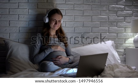Crying pregnant woman watching movie at night, feeling lonely and depressed Royalty-Free Stock Photo #1497946556
