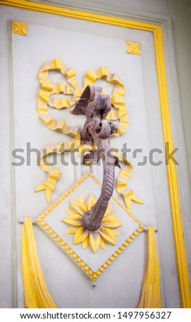 an elegant metal handle on a wooden door that is decorated with carved ribbons and flowers