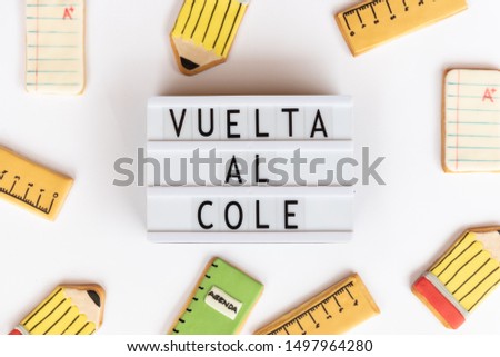 Back to school concept. The text vuelta al cole  in a lightbox (back to school in spanish),  on a white background and surrounded by fondant cookies with designs related to school life